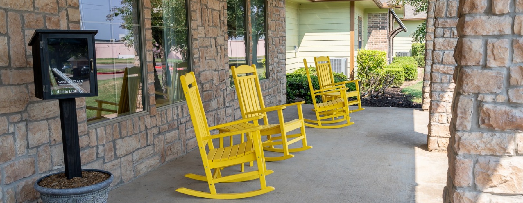yellow rocking chairs on a porch of a brick building